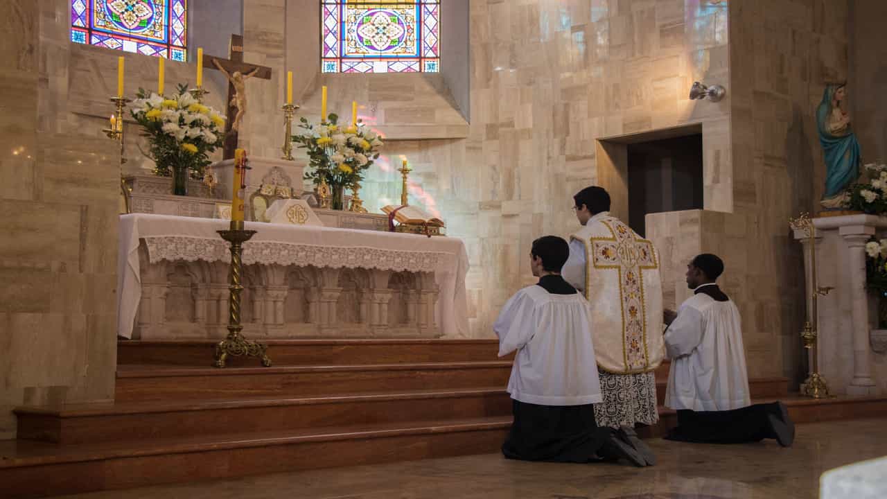 El sacerdote y los monaguillos junto al altar